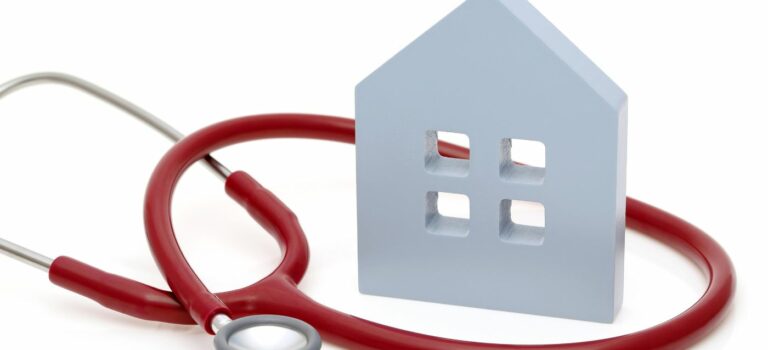 Maison miniature entouree d'un stetoscope pour illustrer le diagnostic immobilier