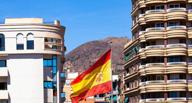 Un drapeau espagnol entre deux immeuble pour illustrer l'immobilier en Espagne