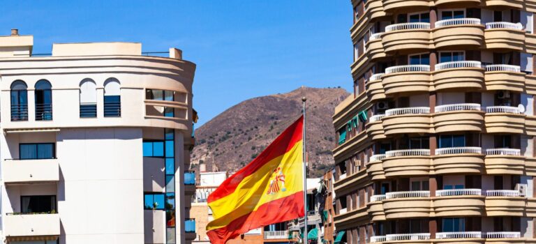 Un drapeau espagnol entre deux immeuble pour illustrer l'immobilier en Espagne