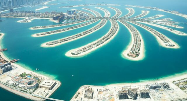 Vue aérienne de Palm Jumeirah à Dubaï, montrant les branches en forme de palmier entourées par les eaux turquoise, avec la ligne d'horizon urbaine en arrière-plan