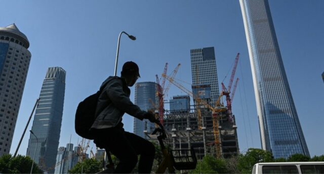 Silhouette d'une personne a velo devant des gratte-ciel et des chantiers de construction à Pekin, Chine