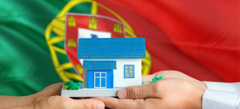 Couple tenant dans ses mains une maison miniature avec le drapeau portugais en toile de fond pour illustrer l'immobilier au Portugal