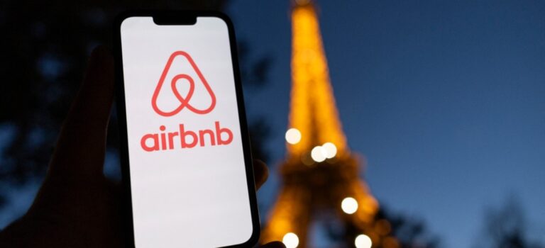 Smartphone avec le logo airbnb et la tour eiffel en toile de fond