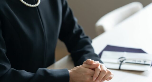 personne habillee en noir les mains posees sur la table suggerant un deuil ou une succession