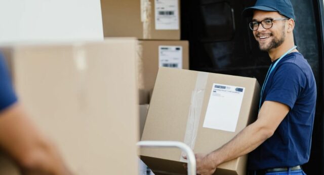 des demenageurs avec des cartons dans les bras devant le camion de demenagement