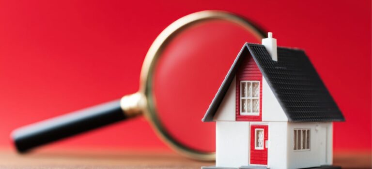 loupe posee sur une maison miniature pour illustrer l'estimation immobiliere