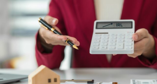 Agent immobilier montrant une calculatrice avec une flèche pointant l’IRL, symbole de l’indexation des honoraires de location en 2026