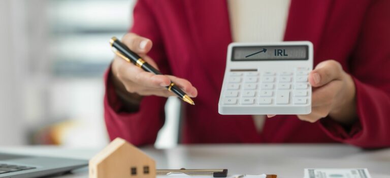 Agent immobilier montrant une calculatrice avec une flèche pointant l’IRL, symbole de l’indexation des honoraires de location en 2026