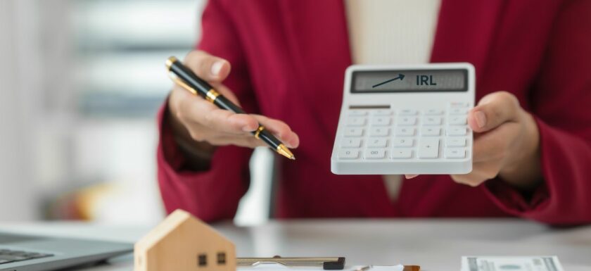 Agent immobilier montrant une calculatrice avec une flèche pointant l’IRL, symbole de l’indexation des honoraires de location en 2026