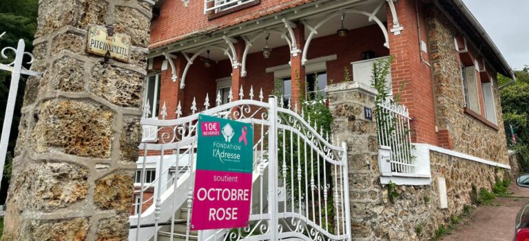 Reseau immobilier l’Adresse mobilise pour Octobre Rose 2025 avec un panneau solidaire devant une maison