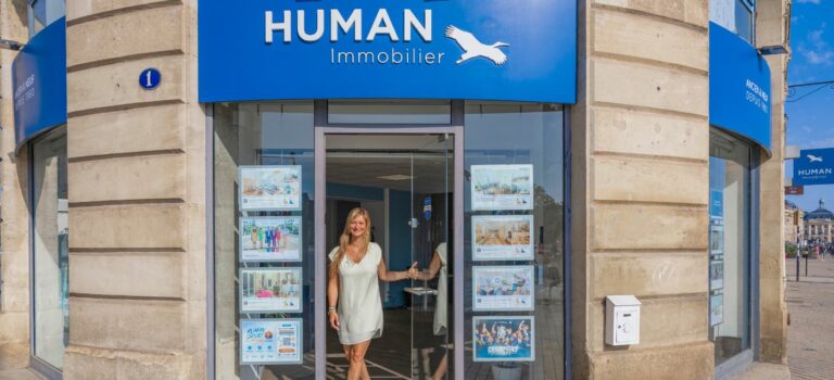 Portrait d’une agente immobilière souriante devant son agence Human