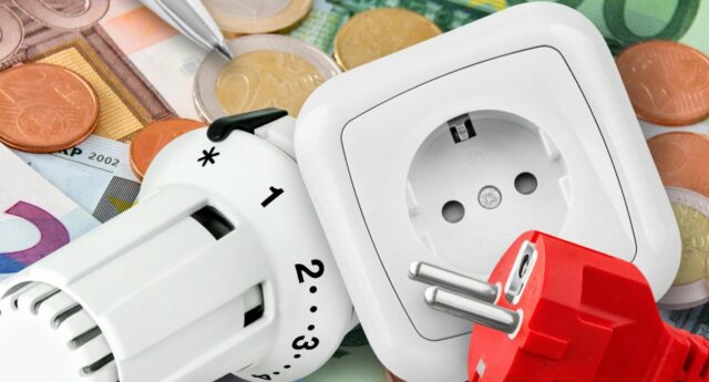 thermostat, prise électrique et fiche rouge poses sur des billets et pieces d’euros.