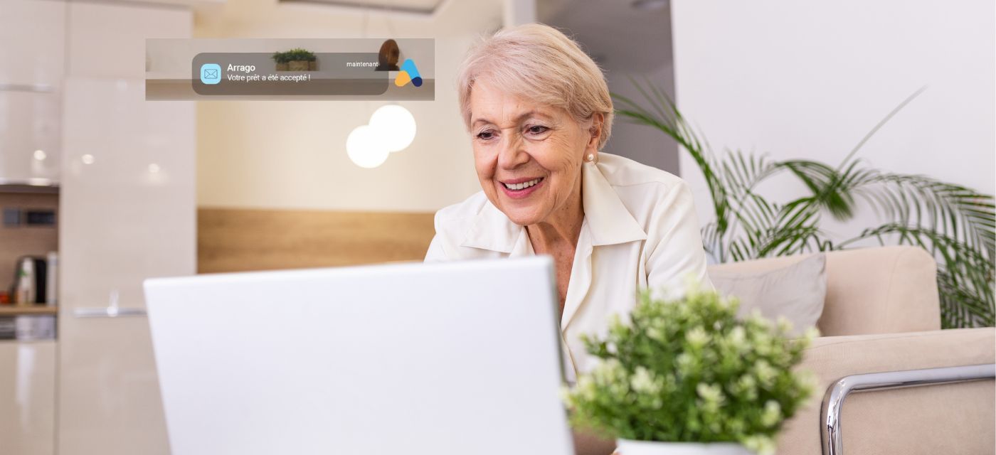 dame senior souriant devant son ordinateur pour illustrer pret viager hypothecaire arrago