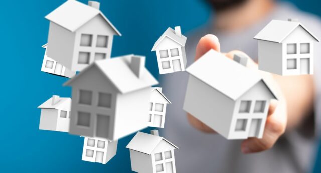 Main selectionnant des maisons symboliques representant le marche immobilier.