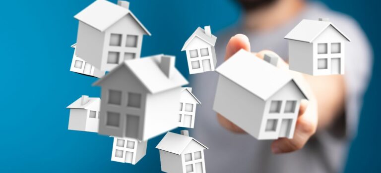 Main selectionnant des maisons symboliques representant le marche immobilier.