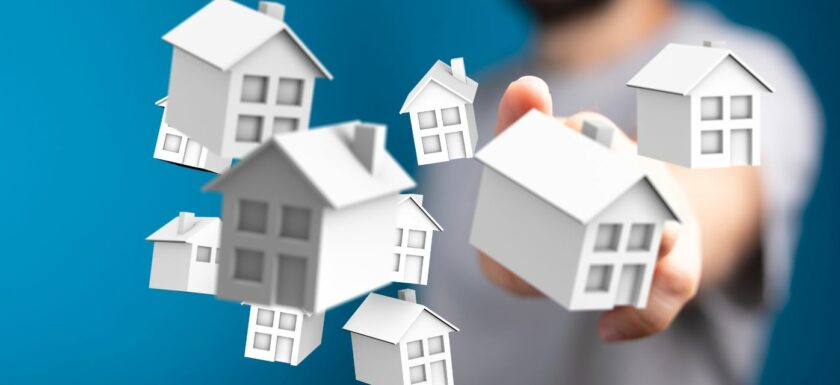 Main selectionnant des maisons symboliques representant le marche immobilier.