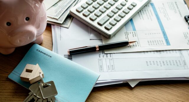 Documents financiers, calculatrice et tirelire illustrant un rachat de credit immobilier