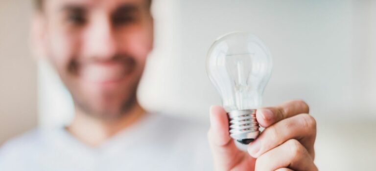 Homme souriant tenant une ampoule electrique dans sa main