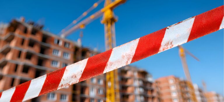 Chantier immobilier à l’arret avec grue et ruban de securité illustrant les difficultes des entreprises du secteur immobilier en 2026