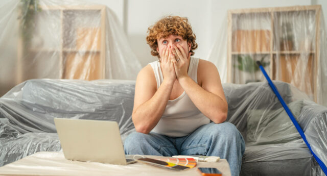 Propriétaire inquiet face au budget des travaux après un achat immobilier, en train de consulter ses dépenses sur ordinateur