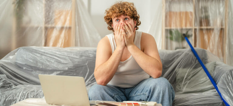 Propriétaire inquiet face au budget des travaux après un achat immobilier, en train de consulter ses dépenses sur ordinateur