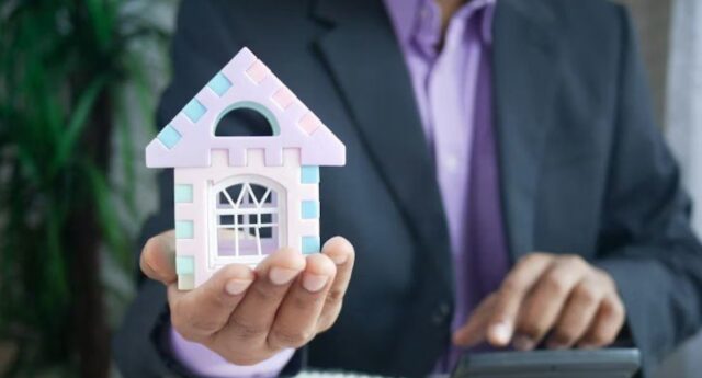Investisseur immobilier tenant une maison miniature pour illustrer la gestion des charges et de la tresorerie locative.