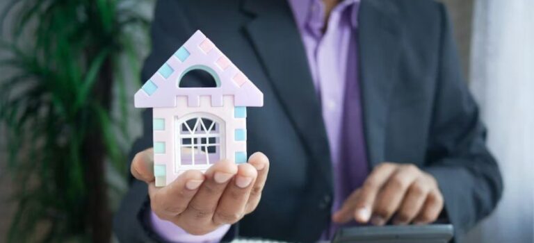 Investisseur immobilier tenant une maison miniature pour illustrer la gestion des charges et de la tresorerie locative.