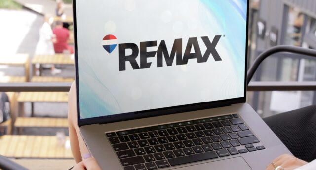 Logo RE/MAX affiché sur un ordinateur portable, symbole du rachat du reseau immobilier par The Real Brokerage.