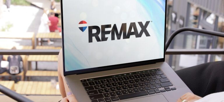 Logo RE/MAX affiché sur un ordinateur portable, symbole du rachat du reseau immobilier par The Real Brokerage.