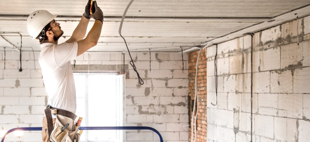 Electricien installant des câbles dans un logement en cours de renovation.