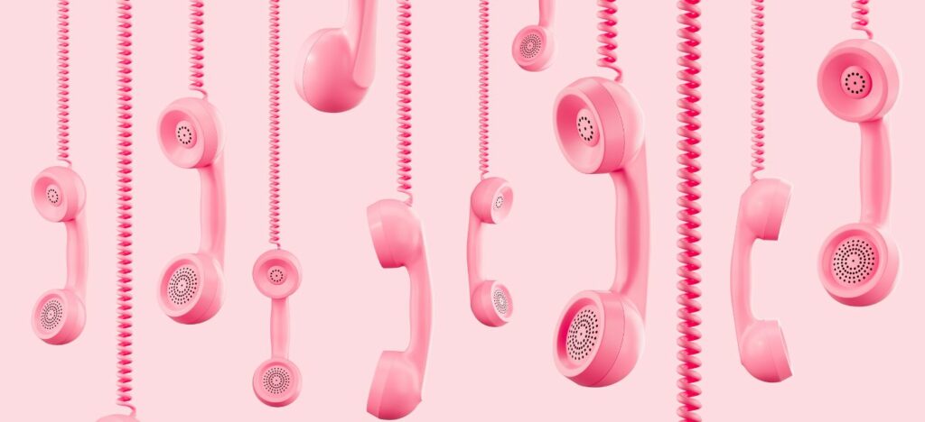 Plusieurs combines telephoniques roses suspendus sur fond rose clair