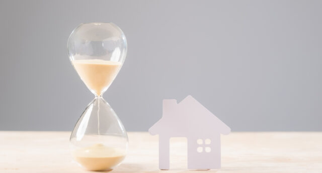 n sablier a cote d’une maison symbolise les délais de vente immobiliere