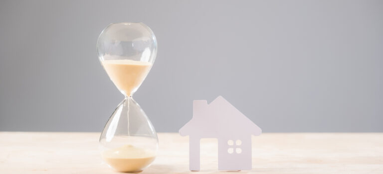 n sablier a cote d’une maison symbolise les délais de vente immobiliere