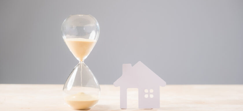n sablier a cote d’une maison symbolise les délais de vente immobiliere