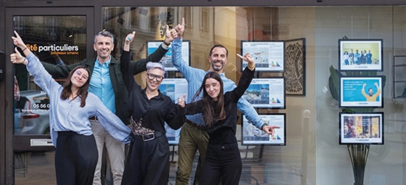L’équipe d’une agence immobilière Côté Particuliers devant sa vitrine
