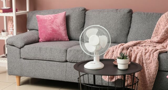 Ventilateur dans un salon aux volets partiellement fermés pendant une journée chaude