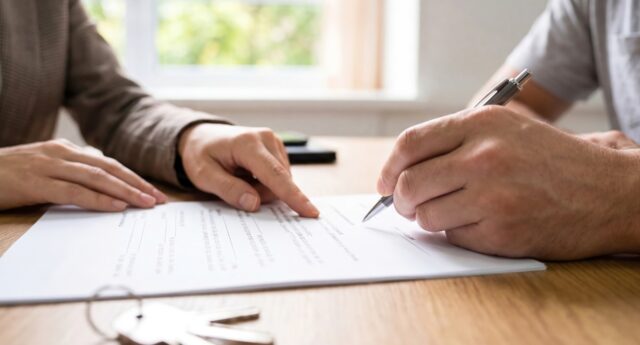 Signature d'un nouveau bail de location : un professionnel montre une clause du contrat type au locataire