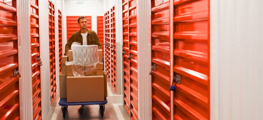 Un homme transporte des cartons et un fauteuil vers un box de stockage
