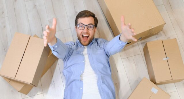 Un jeune locataire souriant entouré de cartons de déménagement