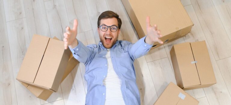 Un jeune locataire souriant entouré de cartons de déménagement
