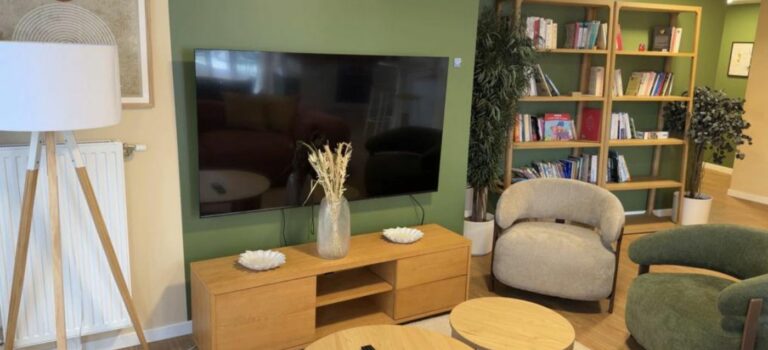 Salle TV de la résidence CRISTAL à Clichy, avec fauteuils, bibliothèque et télévision.