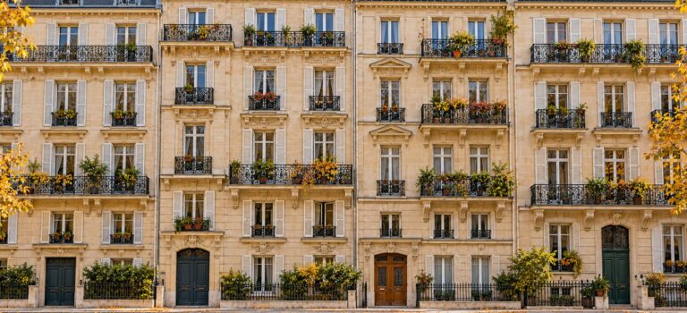 Vue large de façades d’immeubles résidentiels de style parisien, avec balcons et arbres en automne