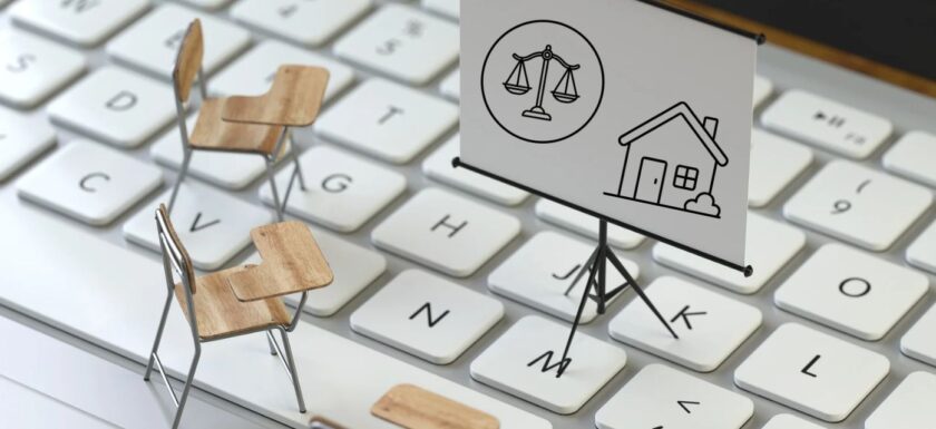 Chaises d’école miniatures sur un clavier face à un tableau avec une balance et une maison, pour la formation des agents immobiliers