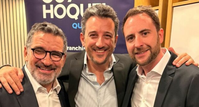 Trois hommes posent devant une signalétique Guy Hoquet Québec.