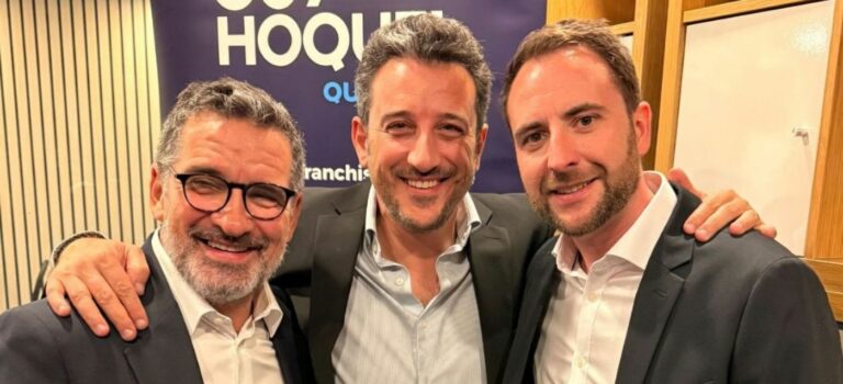 Trois hommes posent devant une signalétique Guy Hoquet Québec.