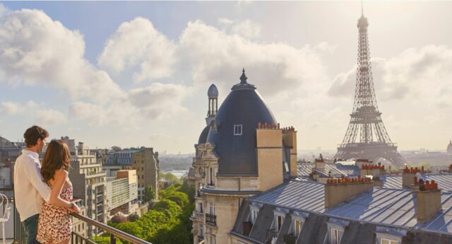 Deux jeunes adultes visitent un appartement parisien avec vue sur des immeubles haussmanniens