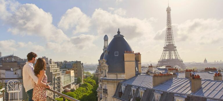 Deux jeunes adultes visitent un appartement parisien avec vue sur des immeubles haussmanniens