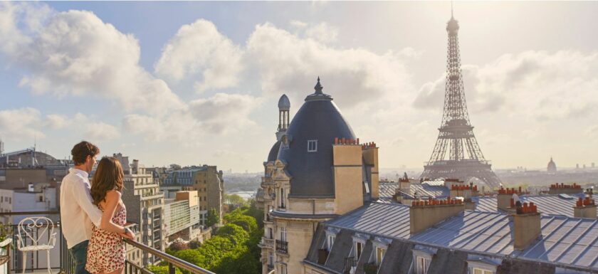 Deux jeunes adultes visitent un appartement parisien avec vue sur des immeubles haussmanniens