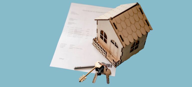Maison miniature en bois posée sur un document de financement immobilier, avec un trousseau de clés au premier plan.
