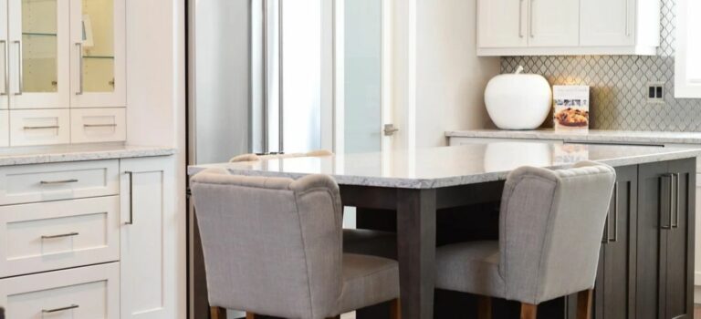 Cuisine moderne avec meubles blancs, îlot central et rangements gris, pour illustrer la valorisation d'un logement avant sa vente.